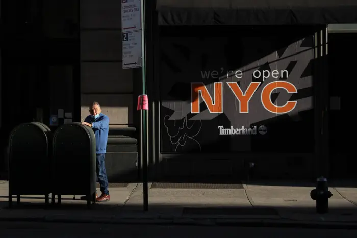 A photo of a person in front of a "we're open NYC" sign